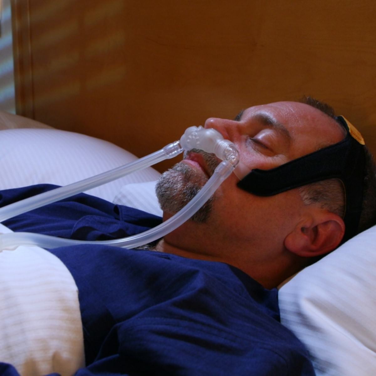 Photo of man using RespCare Bravo II nasal pillow CPAP mask with headgear