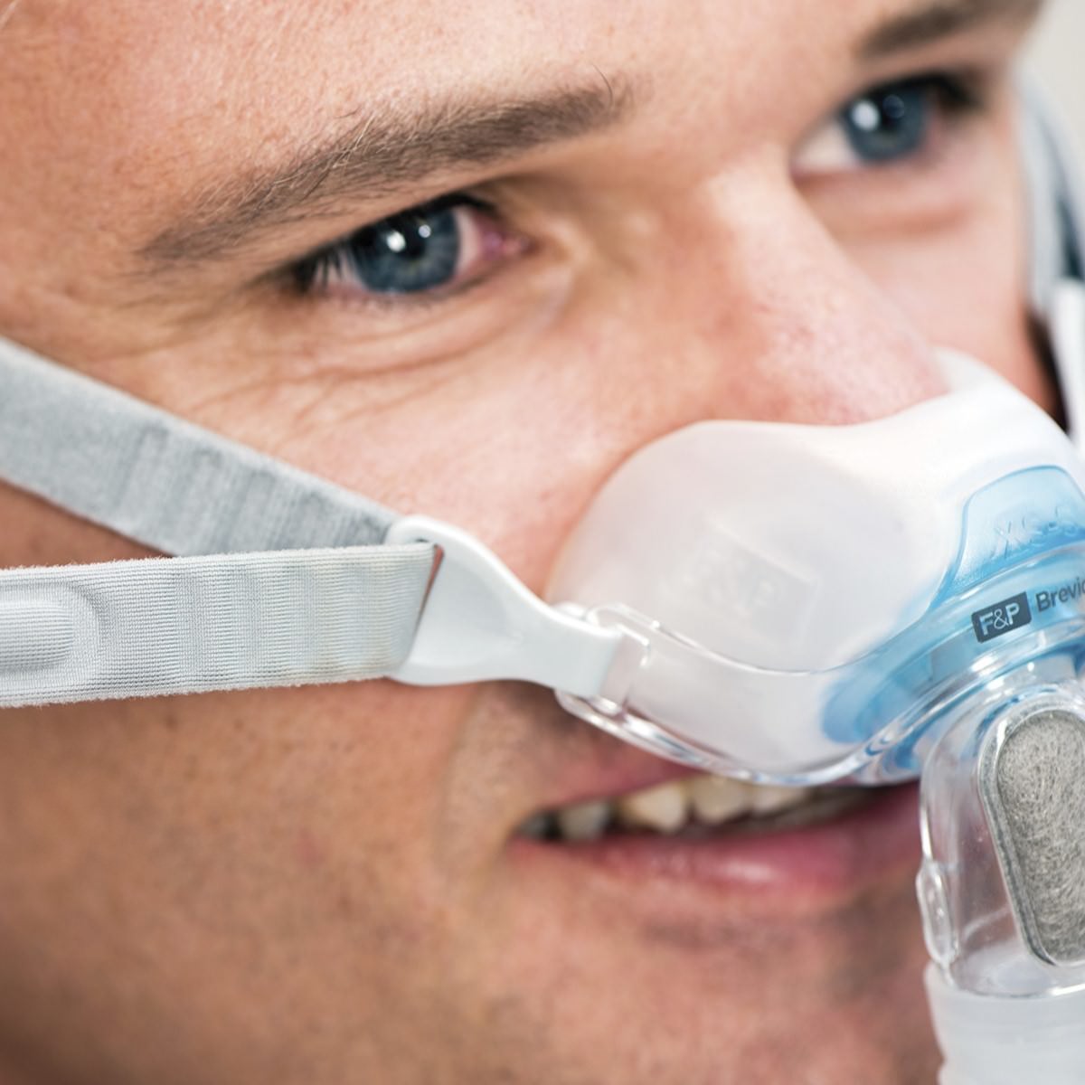 Photo of man wearing Fisher & Paykel Brevida nasal pillow CPAP mask with headgear