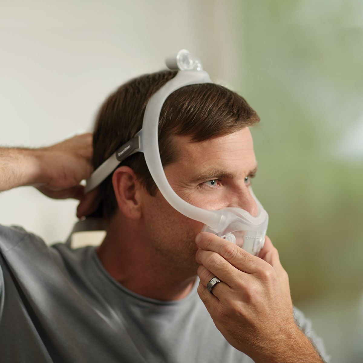 Man Putting on His Philips Respironics DreamWear Full Face Mask W/ Headgear