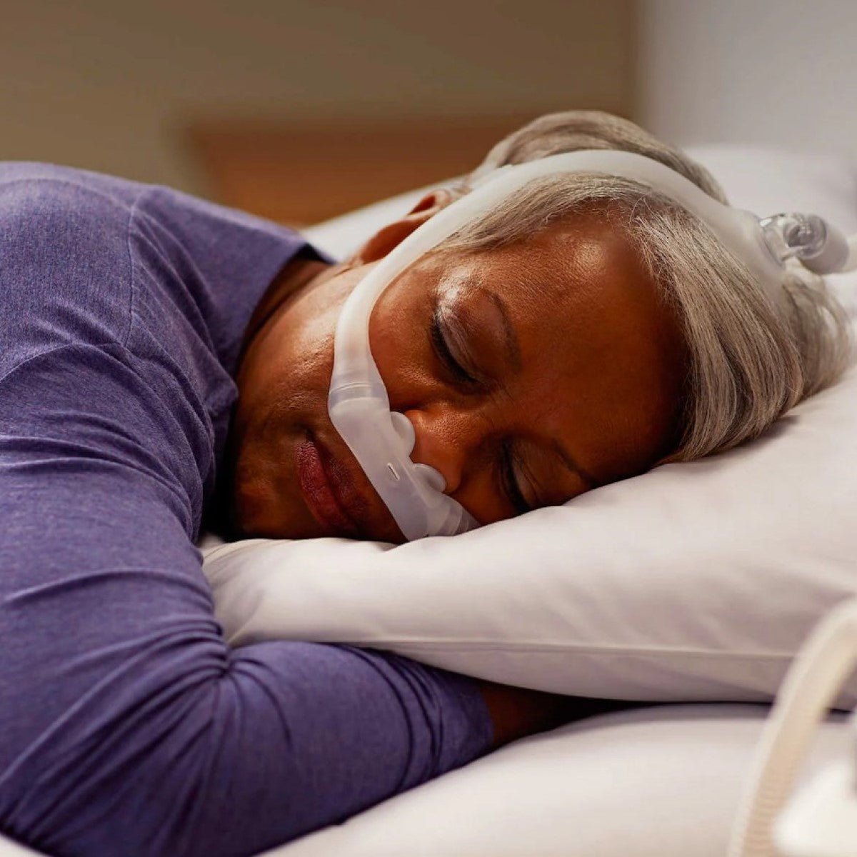 Photo of woman using Philips Respironics DreamWear Silicone nasal pillow CPAP mask kit with headgear