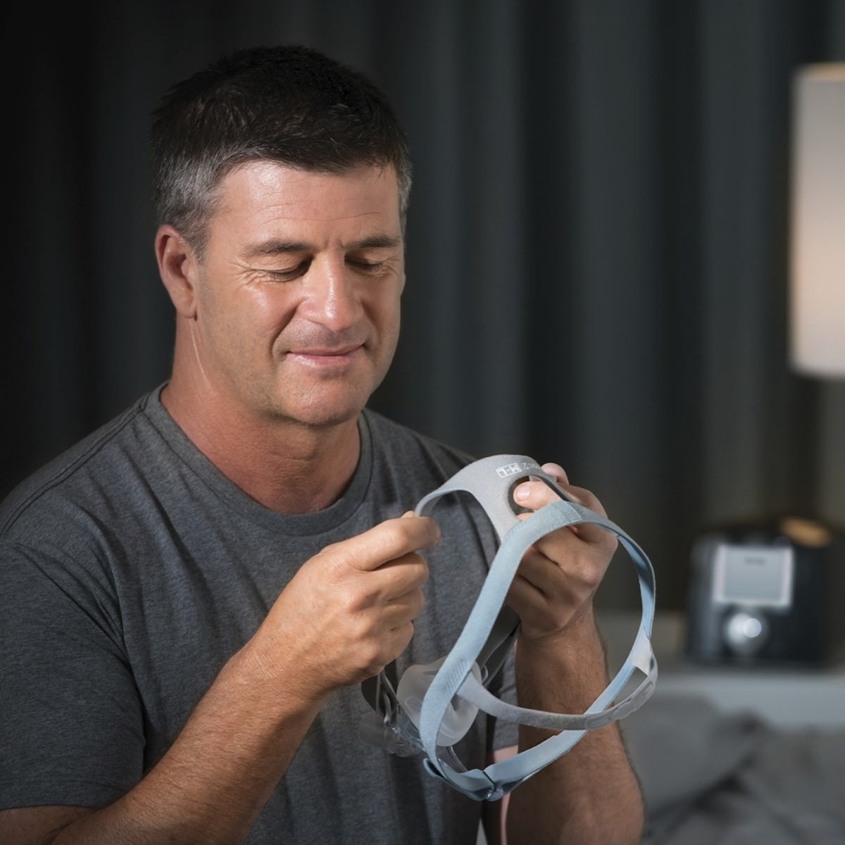 Photo of man holding Fisher & Paykel Eson 2 nasal CPAP mask kit with headgear