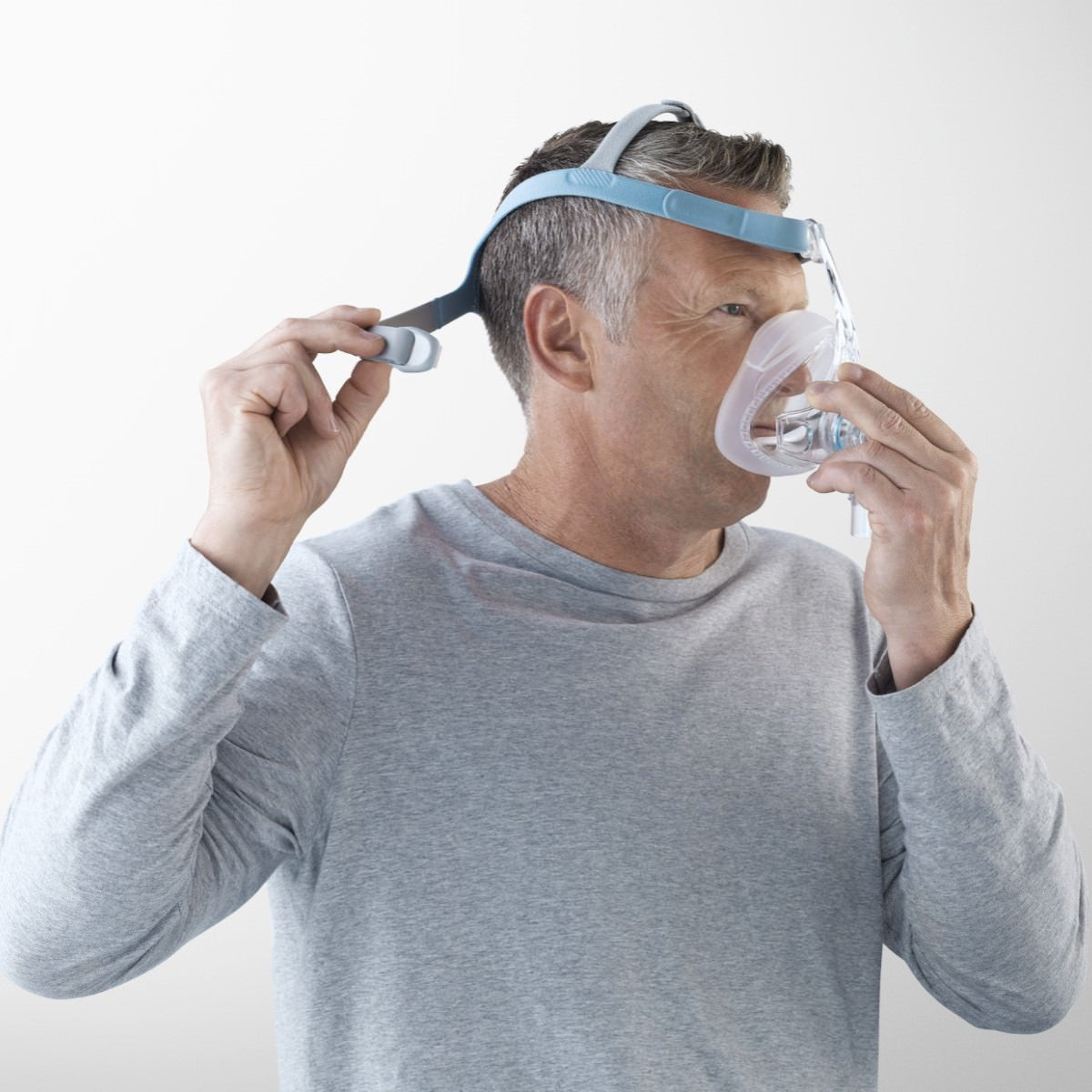 Stock Image of Man Setting Up His Fisher & Paykel Vitera Full Face CPAP Mask W/ Headgear