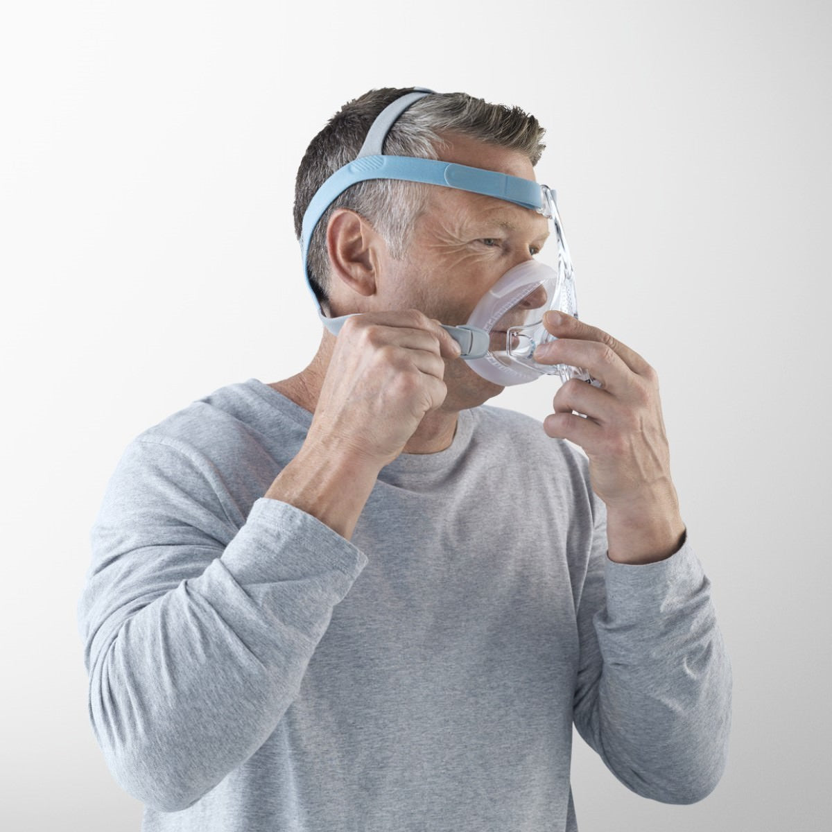 Stock Image of Man Setting Up His Fisher & Paykel Vitera Full Face CPAP Mask W/ Headgear