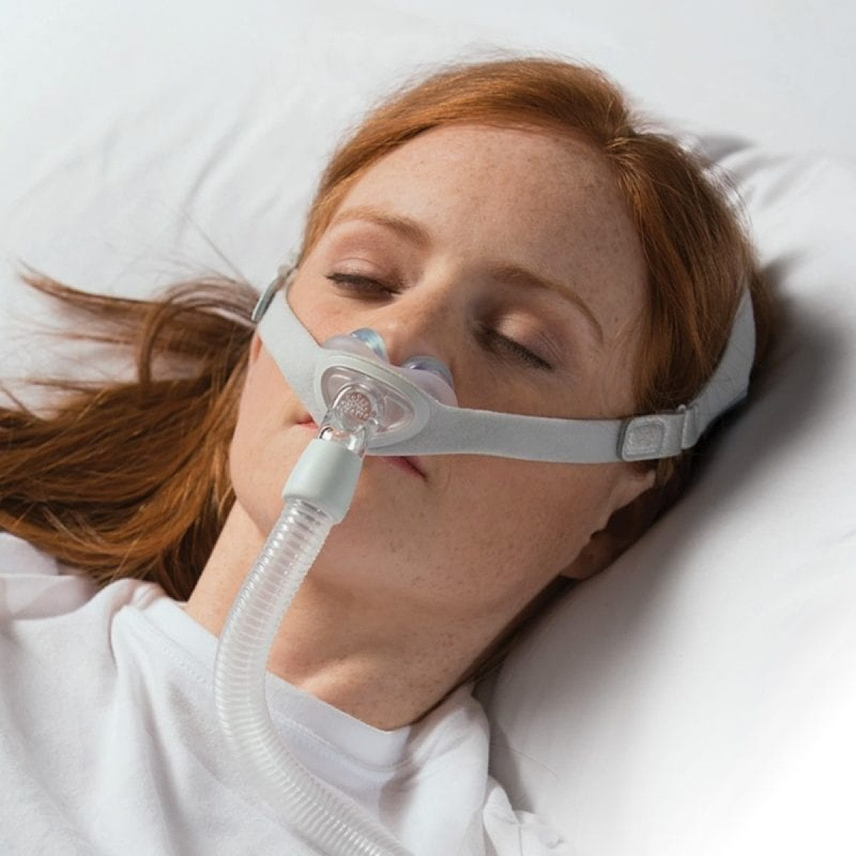 Stock photo of woman using Philips Respironics Nuance Gel nasal pillow CPAP mask fit pack with headgear