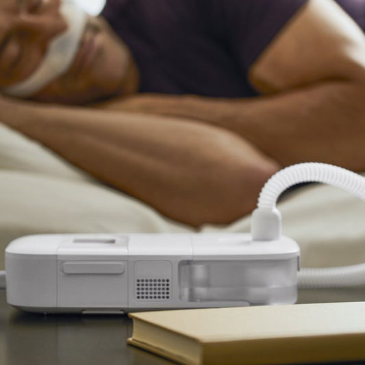Photo of man using Philips Respironics DreamStation Go Auto Travel CPAP machine with humidifier