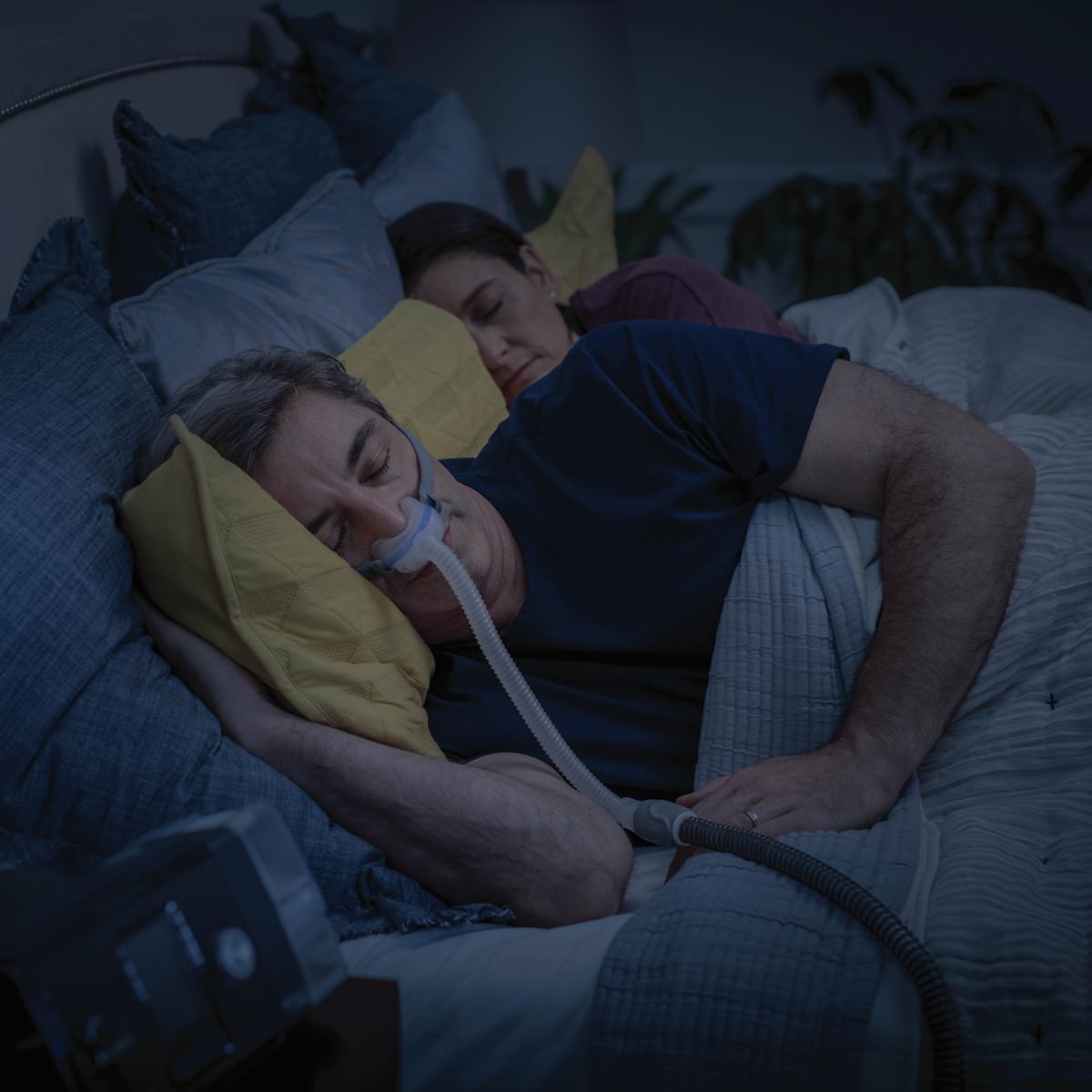 Man Sleeping Wearing His Nasal CPAP Mask Lying Next to His Partner