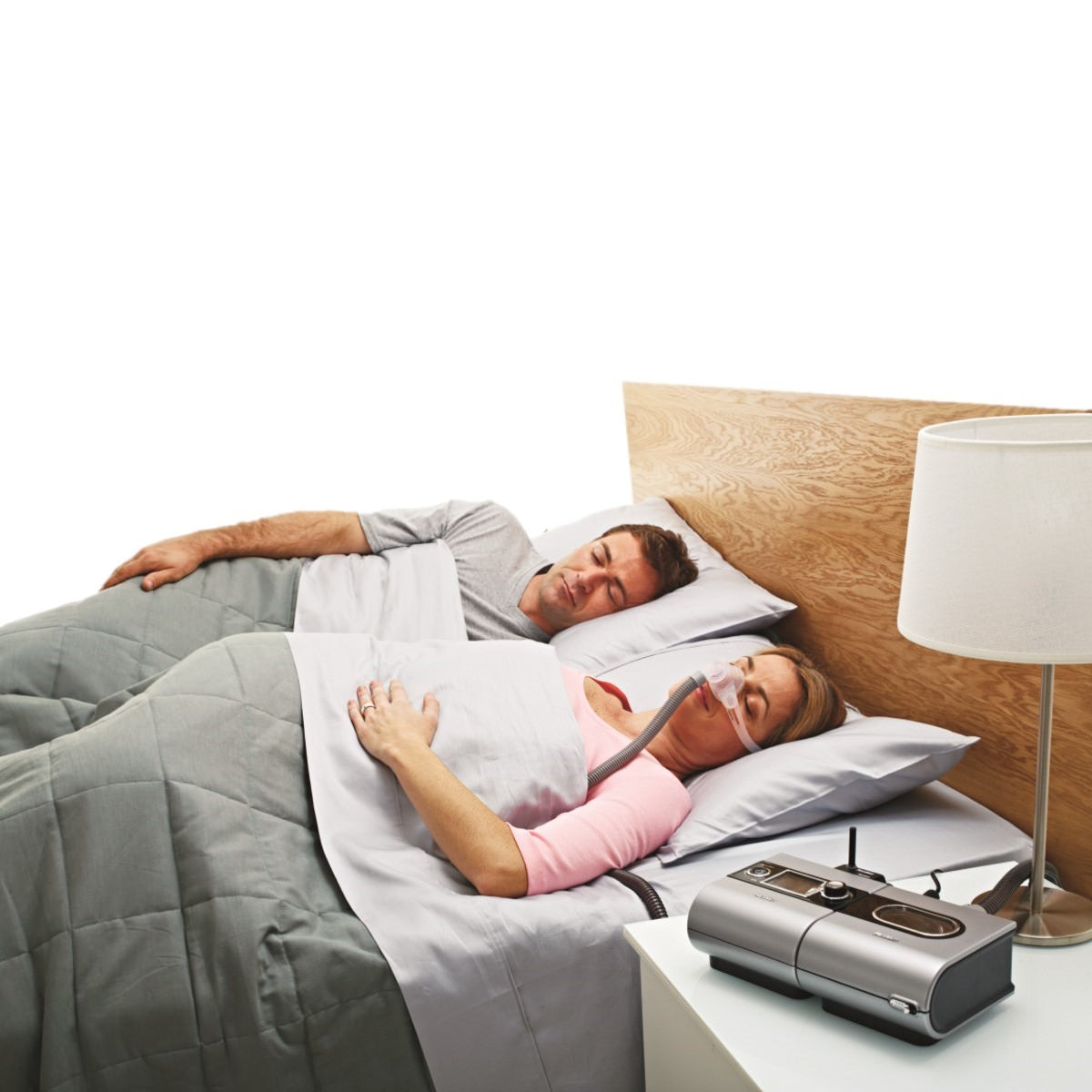 Stock photo of woman sleeping in bed wearing ResMed Swift FX nano for her nasal pillow CPAP mask with headgear