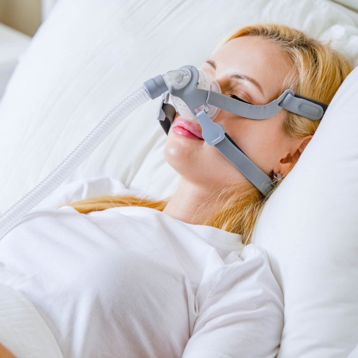 Stock Image of Woman Sleeping Wearing React Health's Siesta Nasal CPAP Mask W/ Headgear