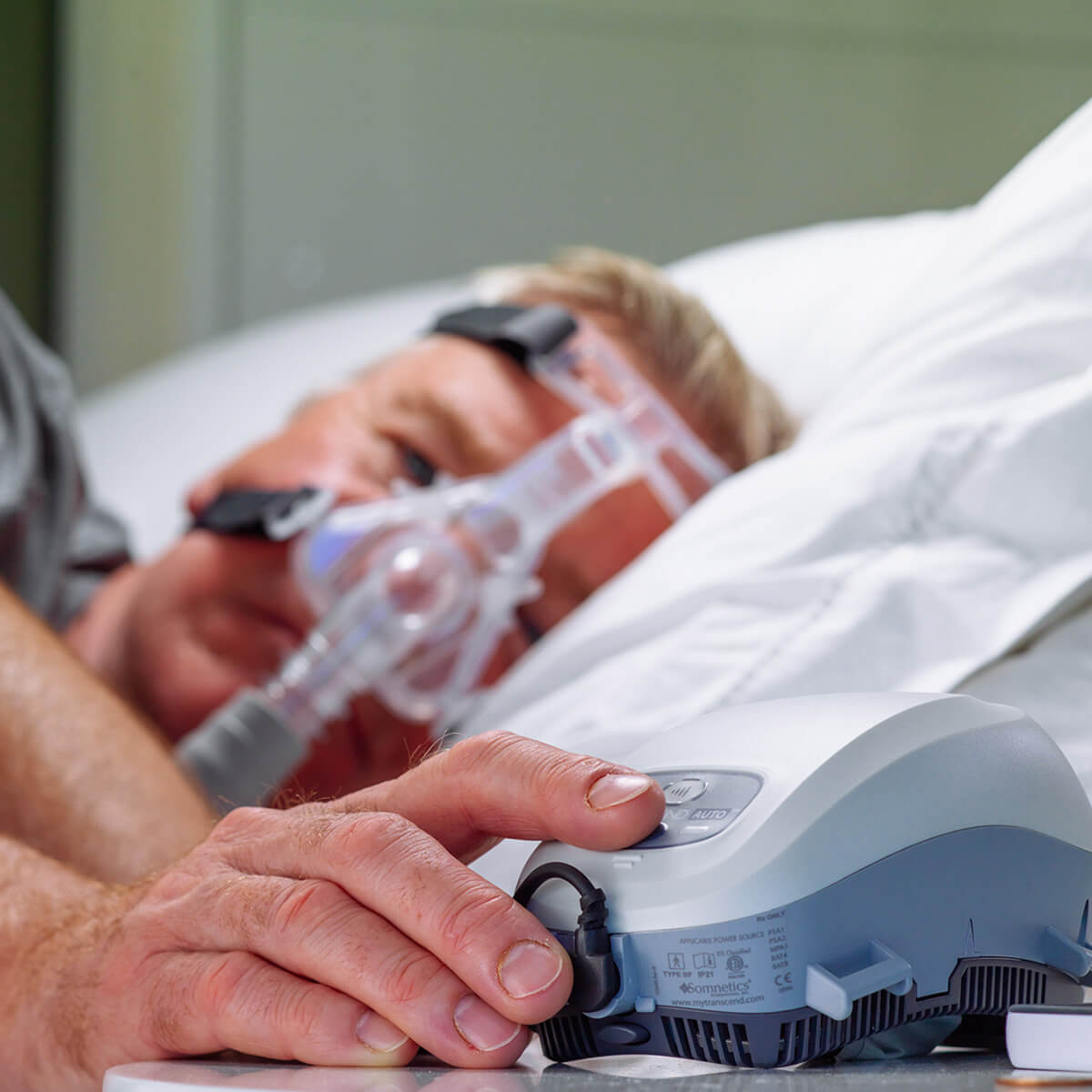Man turning on a Somnetics Transcend Mini Auto CPAP With EZEX CPAP machine