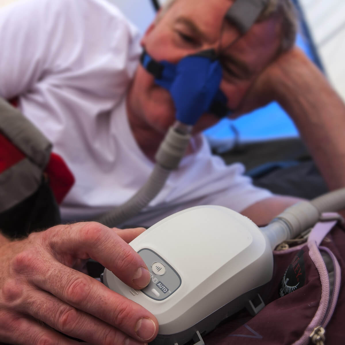 Man Sleeping in Tent Using His Somnetics Transcend Auto CPAP Machine