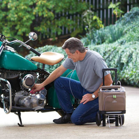 Man Using Respironics SimplyGo Mobile Oxygen Cart While Cleaning His Motorcycle