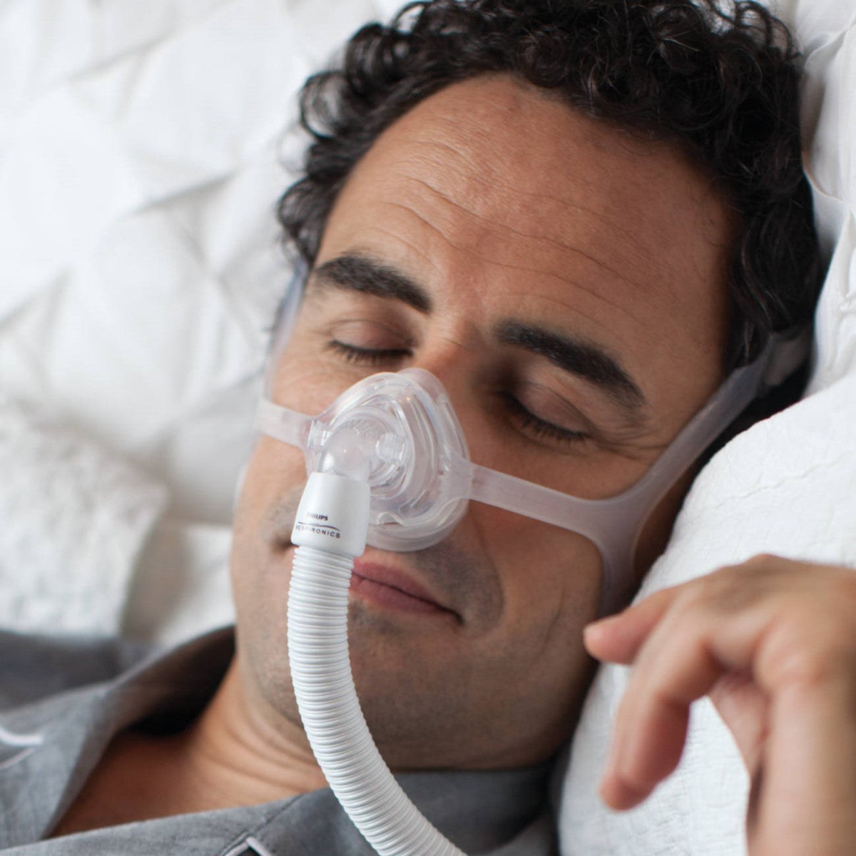 Man sleeping while wearing a Philips Respironics Wisp Clear nasal CPAP mask fit pack
