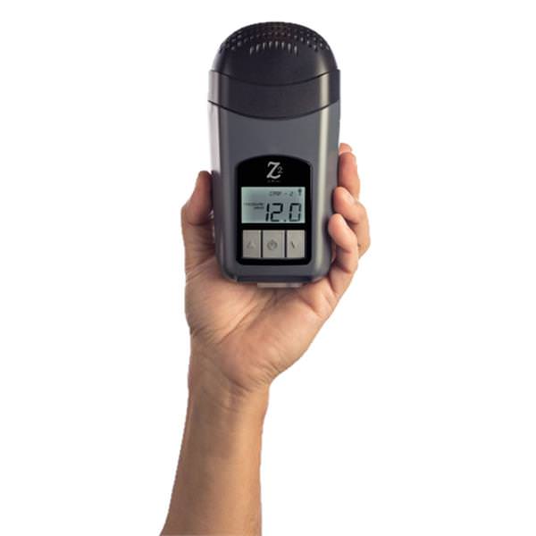 Stock photo of a hand holding the Breas Z2 auto travel CPAP machine