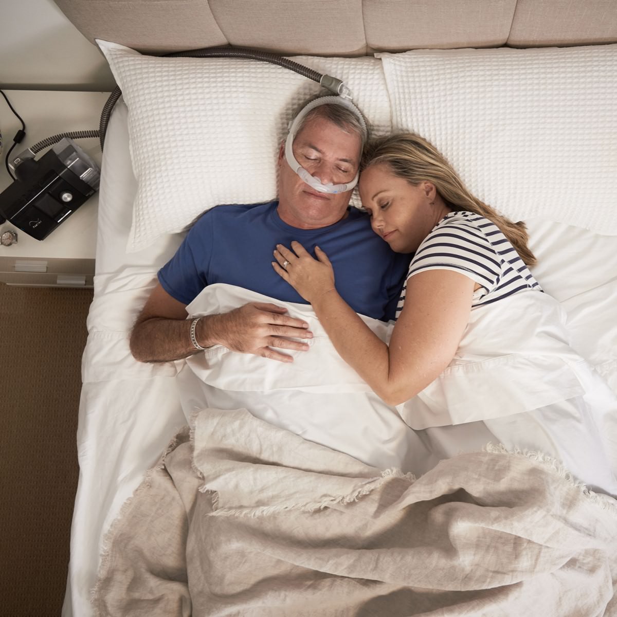 Man Using His CPAP Machine & Accessories While Sleeping With Partner in Bed