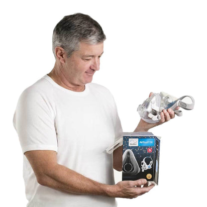 Stock photo of man holding ResMed AirTouch F20 full face CPAP mask with headgear