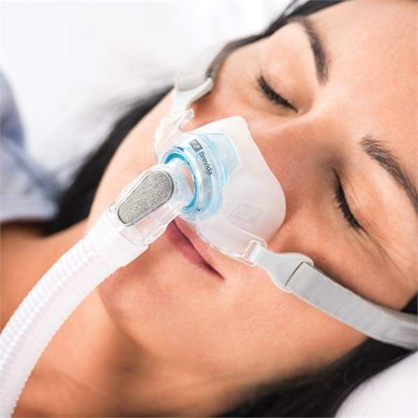 Photo of woman using Fisher & Paykel Brevida nasal pillow CPAP mask with headgear