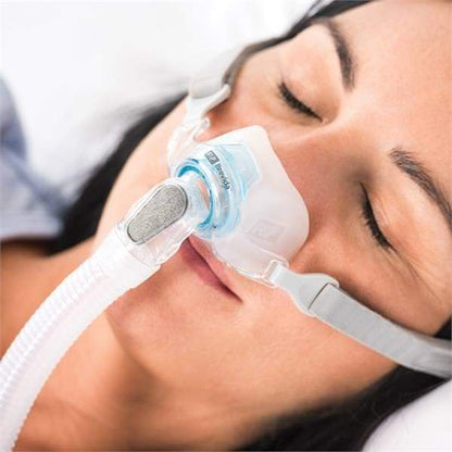 Photo of woman using Fisher & Paykel Brevida nasal pillow CPAP mask with headgear