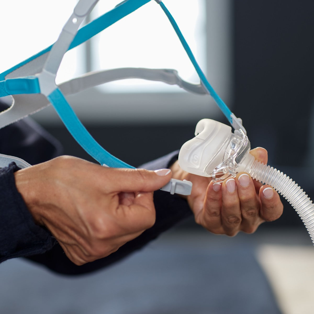 Person holding a CPAP mask and hose with a blurred background