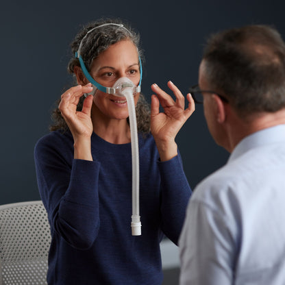 Woman holding a cpap mask with a man in a blue shirt against a dark background