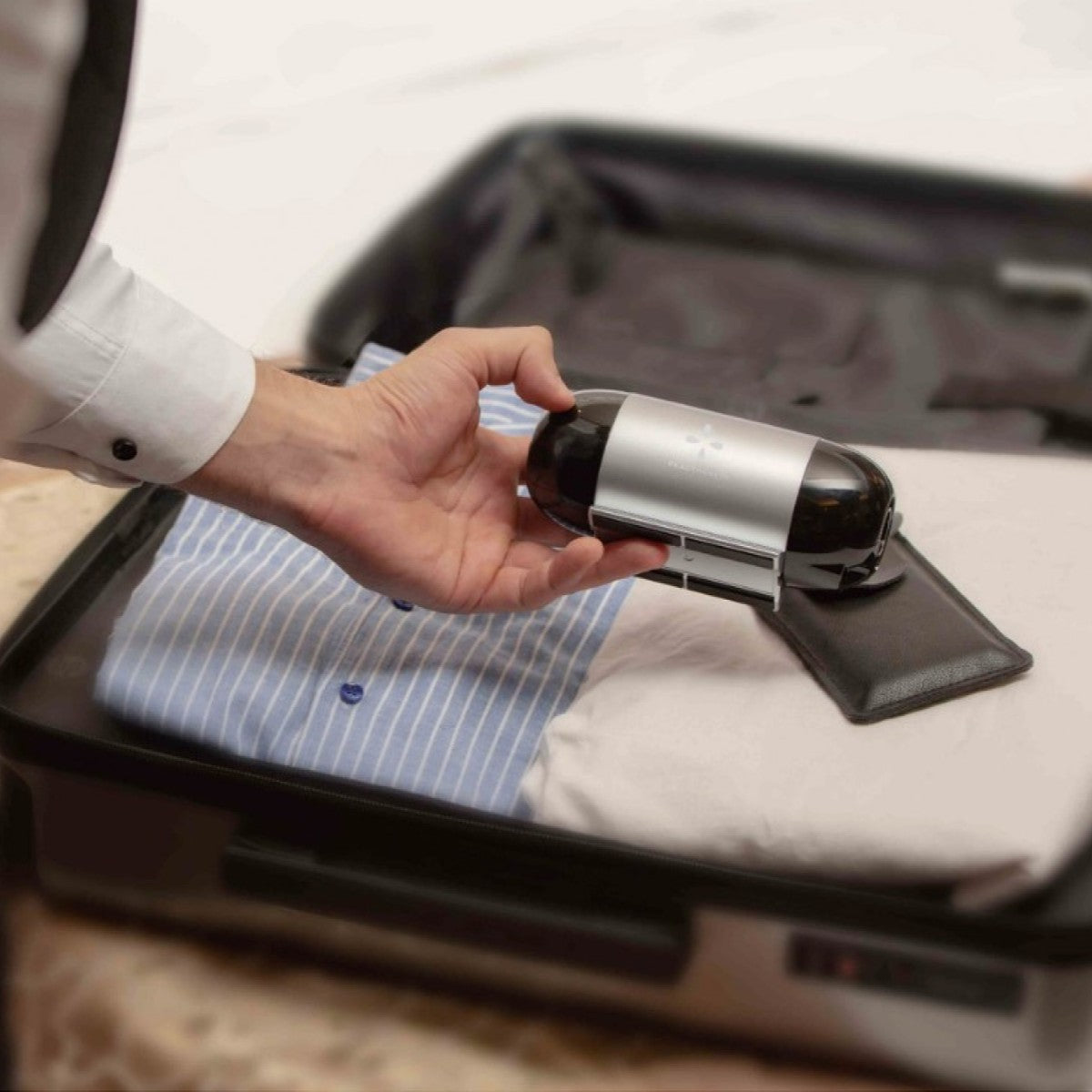 Person packing a travel cpap inside an open suitcase.