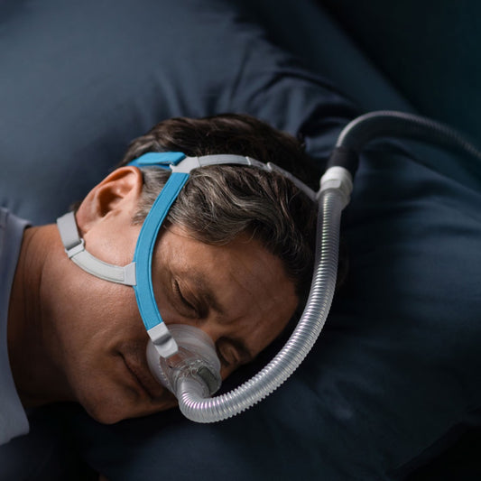 Person sleeping with a CPAP mask and hose on a dark background