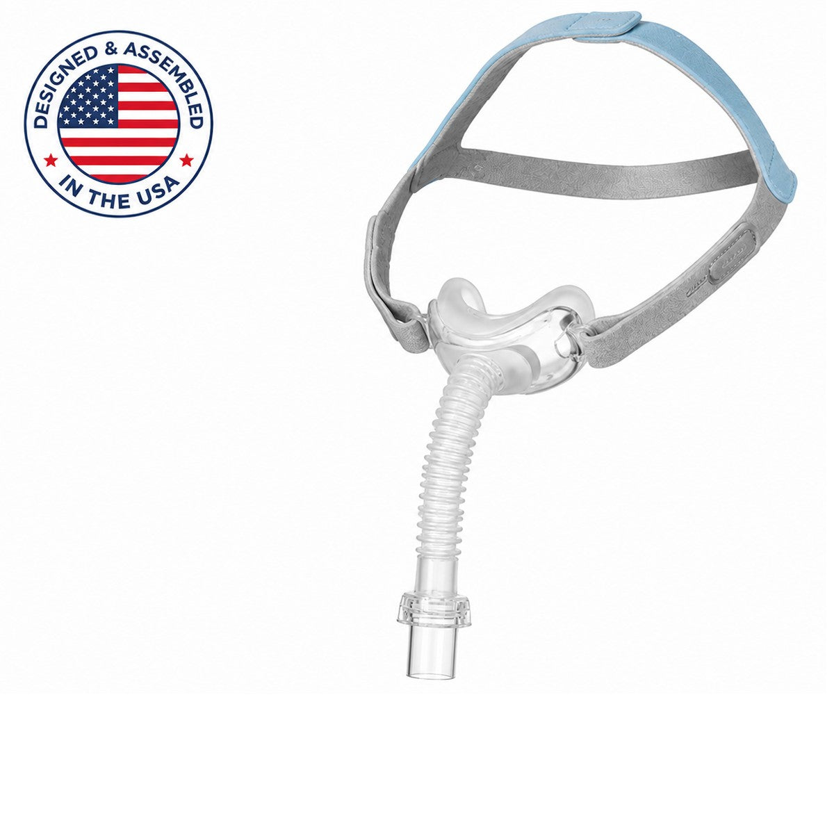 A sleep apnea mask with a clear mouthpiece tube, gray headband straps, and a light blue top strap, shown on a white background with a 'Designed & Assembled in the USA' badge in the top-left corner.