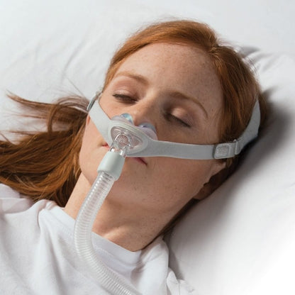 Stock photo of woman using Philips Respironics Nuance Gel nasal pillow CPAP mask fit pack with headgear