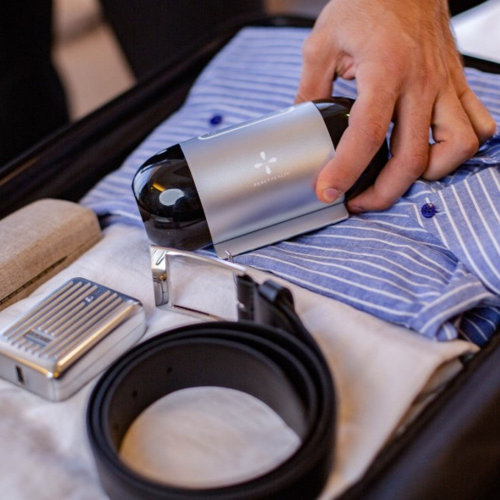 Person using a travel-sized cpap with a  striped shirt with various travel items around.