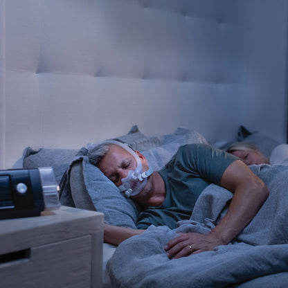 Man sleeping while wearing ResMed AirFit F30i full face CPAP mask with headgear