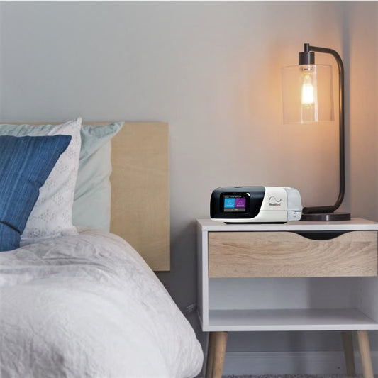 Photo of ResMed AirSense 11 CPAP machine plugged in 65w power supply on night stand