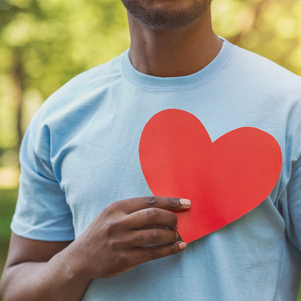 Man Holding a Paper Heart Over His Chest