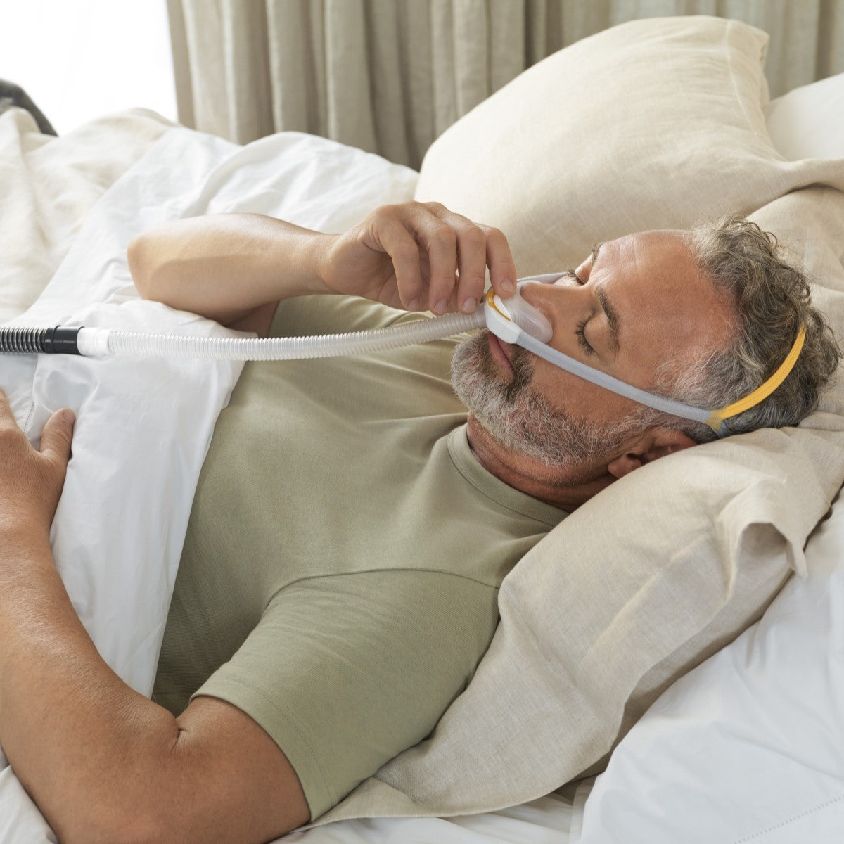 Man Laying Supine Fitting His Fisher & Paykel Solo Nasal CPAP Mask W/ Headgear