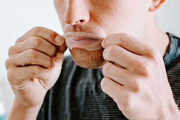 Stock Image of Man Placing on Somnifix Mouth Strips