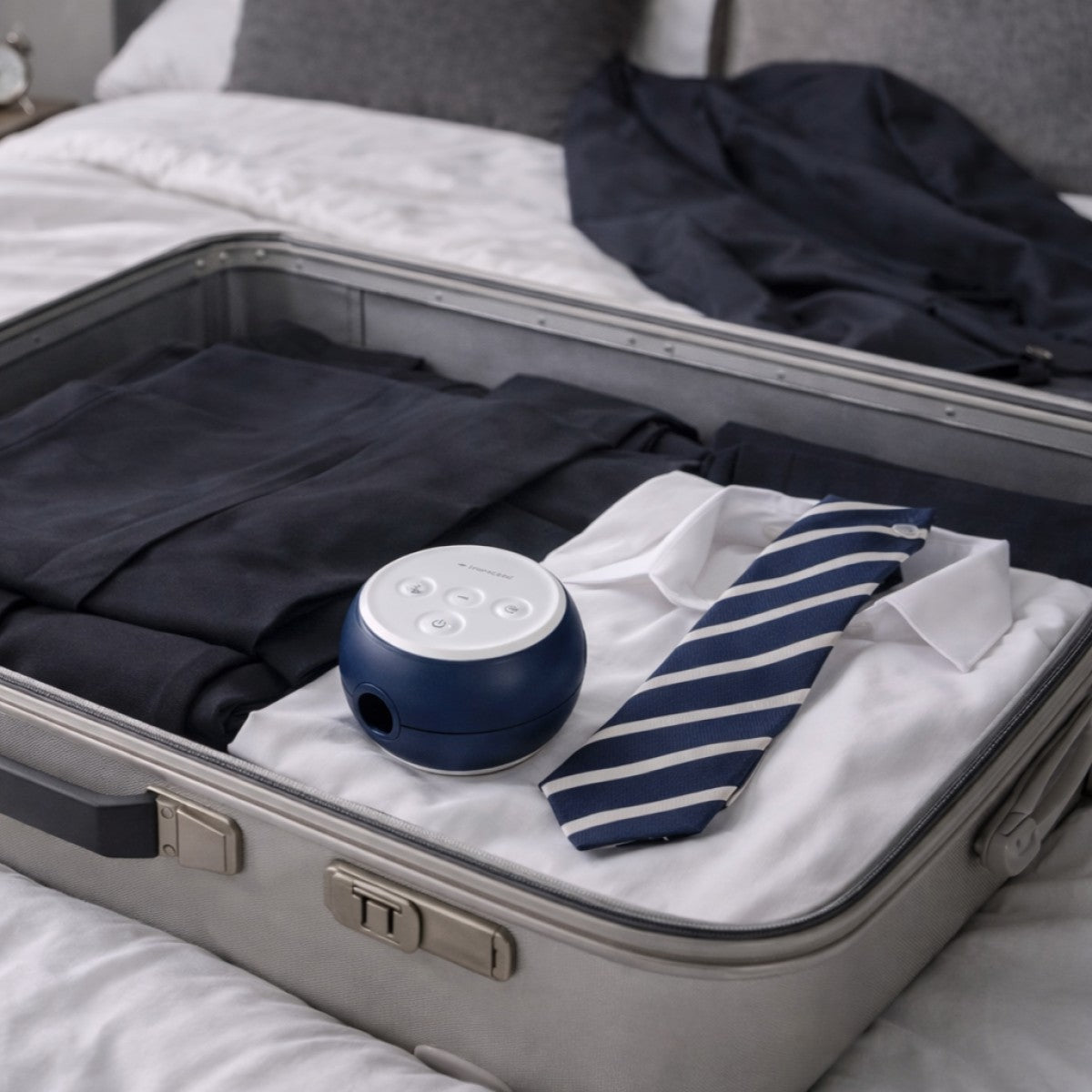 Small blue and white travel CPAP device in an open suitcase with clothes
