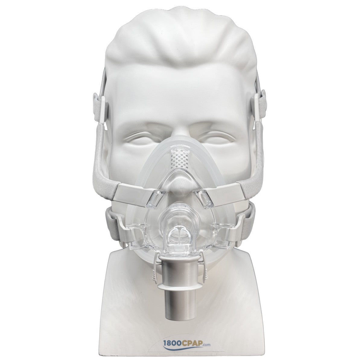 A clear CPAP mask displayed on a white mannequin head and stand against a white background. The mask has a clear facepiece, transparent headgear straps, and a silver valve connector.