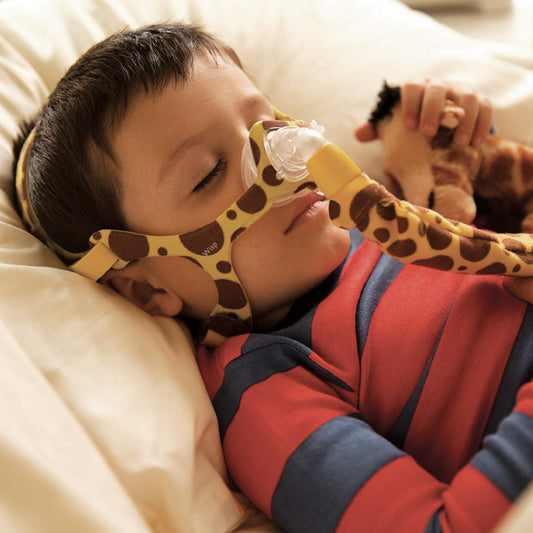 Sleeping kid wearing a giraffe style Philips Respironics Wisp Pediatric nasal CPAP mask fit pack with headgear